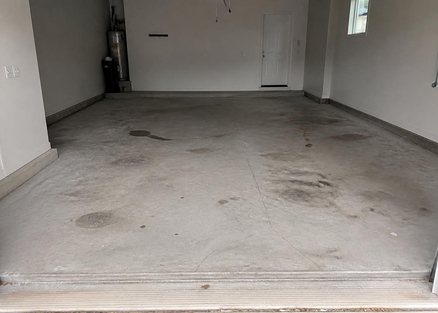 Bare stained and cracked concrete garage floor before coating